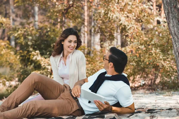 Couple souriant avec tablette reposant sur une couverture sur une plage de sable — Photo de stock