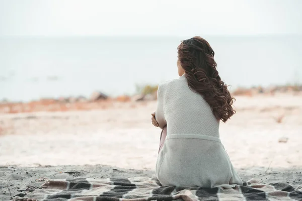 Rückansicht einer Frau, die allein auf einer Decke am Sandstrand ruht — Stockfoto