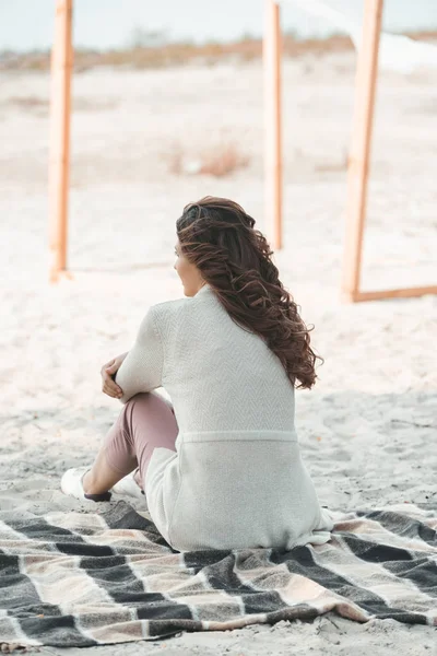 Back view of woman resting on blanket alone on sandy beach — Stock Photo