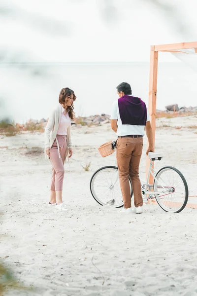 Couple with retro bicycle on sandy beach — Stock Photo