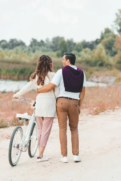Visão traseira do casal com bicicleta retro na praia de areia — Fotografia de Stock