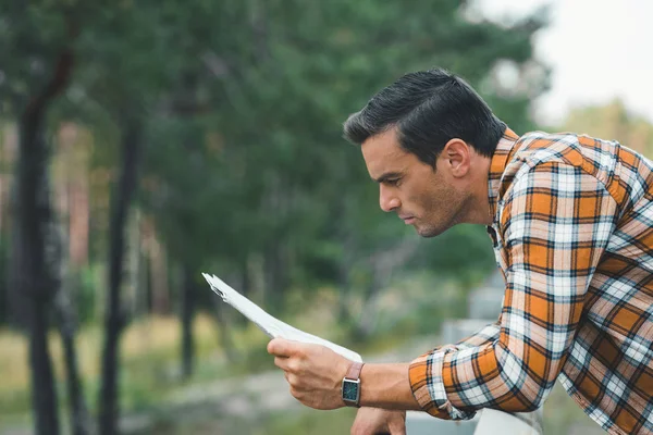 Vue latérale du touriste concentré regardant la carte — Photo de stock