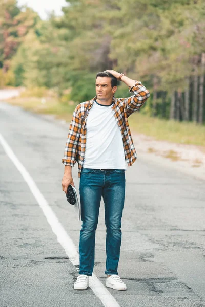 Homem com binóculos e mapa em pé na estrada enquanto viaja sozinho — Fotografia de Stock