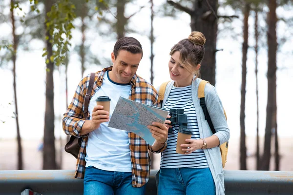 Retrato de pareja sonriente mirando el mapa mientras viajan juntos - foto de stock