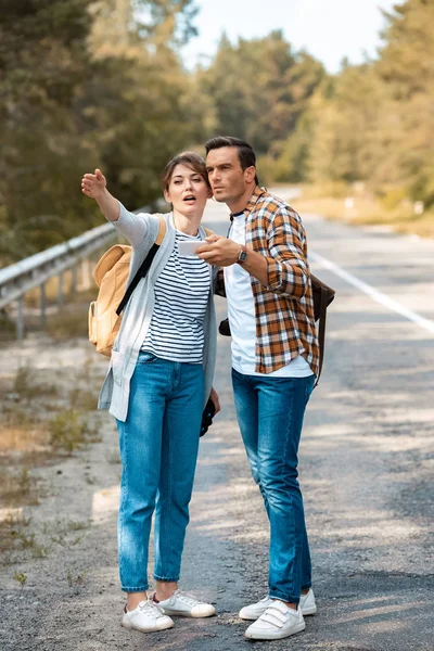 Tourists with smartphone looking for destination while standing on empty road — Stock Photo