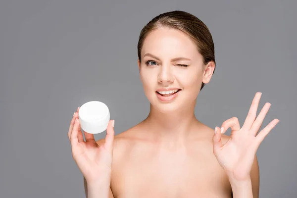 Portrait of beautiful young woman with face cream showing ok sign isolated on grey — Stock Photo