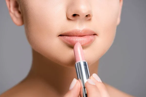 Partial view of woman applying nude lipstick isolated on grey — Stock Photo