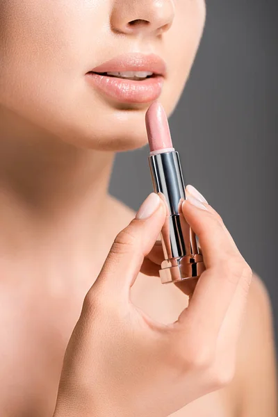 Schnappschuss einer Frau, die nackten Lippenstift isoliert auf Grau aufträgt — Stockfoto