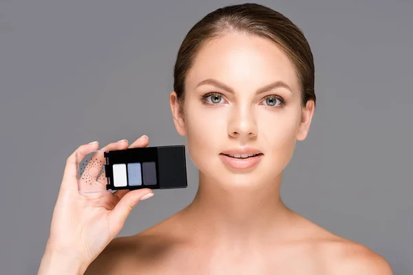 Portrait of young woman showing eyeshadows isolated on grey — Stock Photo