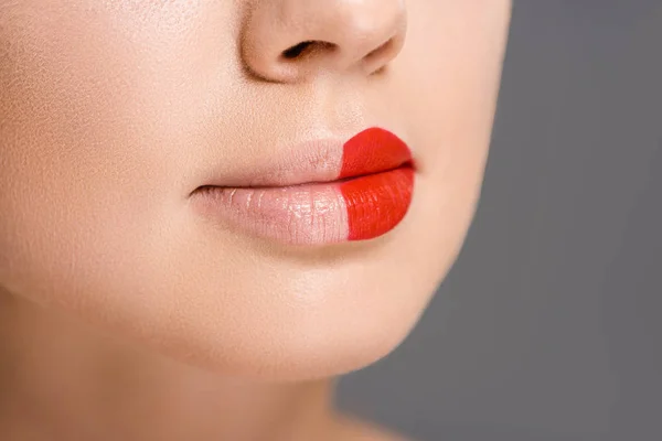 Colpo ritagliato di donna con rossetto rosso su metà bocca isolato su grigio — Foto stock