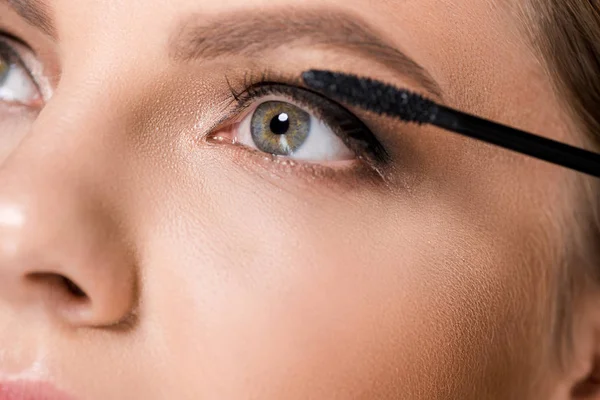 Partial view of woman applying black mascara while looking away — Stock Photo