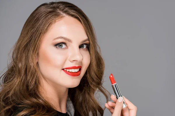 Atractiva mujer sonriente con lápiz labial rojo aislado en gris - foto de stock