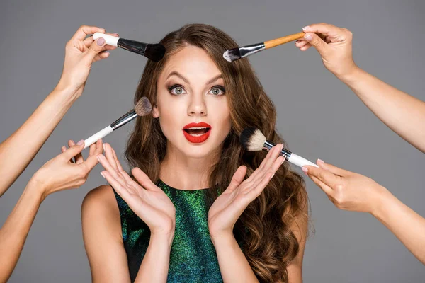 Cropped shot of makeup artists with makeup brushes and shocked woman isolated on grey — Stock Photo
