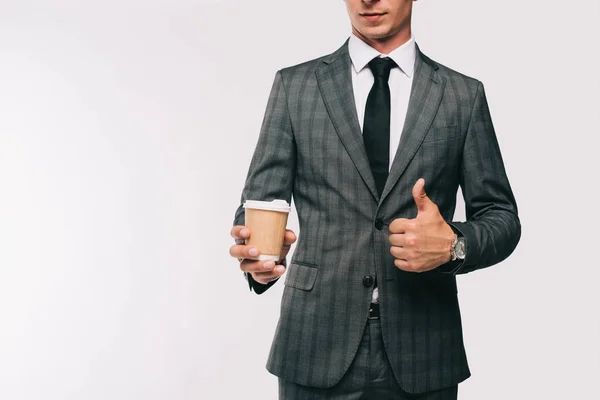 Cropped image of businessman holding coffee in paper cup and showing thumb up isolated on white — Stock Photo