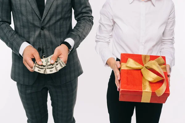Cropped image of businesspeople holding dollars and gift box isolated on white — Stock Photo