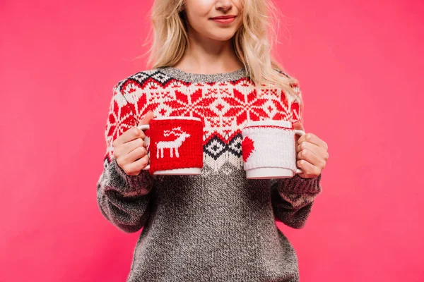 Cropped image of girl in sweater holding two different cups isolated on pink — Stock Photo