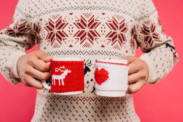 Image recadrée de l'homme tenant des tasses avec silhouette de cerf et coeur isolé sur rose — Photo de stock