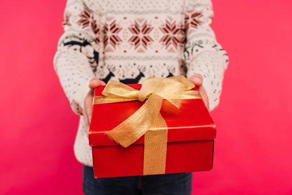 Cropped image of man in sweater showing gift box isolated on pink — Stock Photo