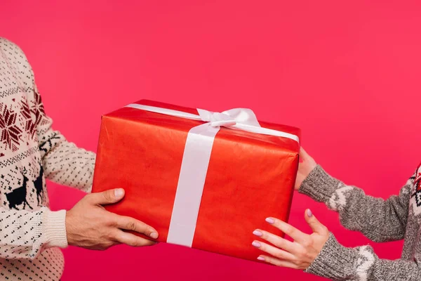 Imagen recortada de novio y novia sosteniendo caja de regalo juntos aislados en rosa — Stock Photo
