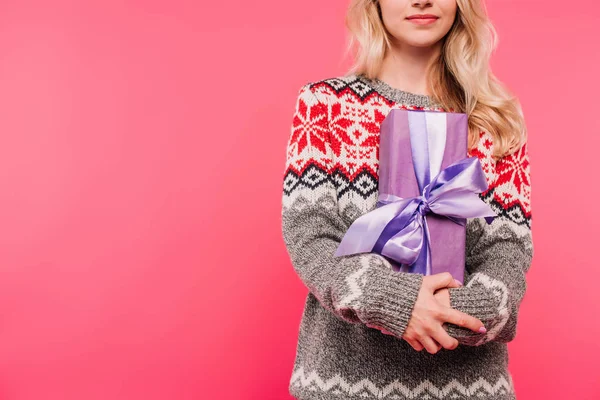 Image recadrée de fille en pull étreinte présent dans la boîte violette isolé sur rose — Photo de stock
