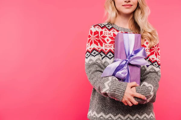 Imagen recortada de niña en suéter abrazo presente en caja violeta aislado en rosa — Stock Photo