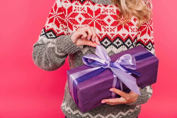 Cropped image of girl in sweater opening present in violet box isolated on pink — Stock Photo