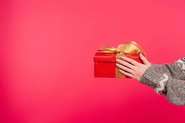 Image recadrée de fille en pull tenant boîte cadeau dans les mains isolées sur rose — Photo de stock