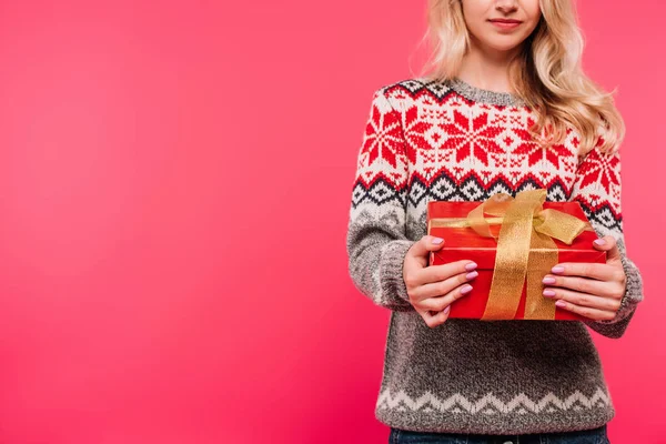 Image recadrée de fille en pull tenant boîte cadeau rouge isolé sur rose — Photo de stock