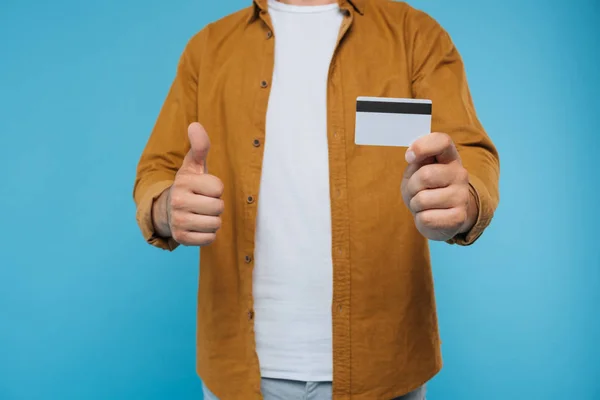Abgeschnittenes Bild eines Mannes, der den Daumen nach oben zeigt und Kreditkarte isoliert auf blauem Grund hält — Stockfoto