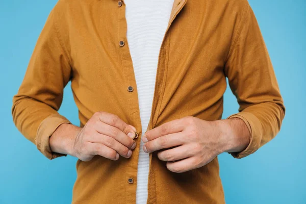 Imagem cortada de homem abotoando camisa marrom isolado em azul — Fotografia de Stock