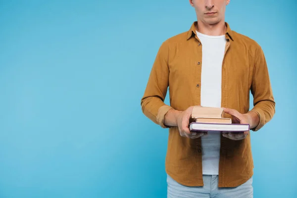 Imagem cortada do homem segurando três livros isolados em azul — Fotografia de Stock