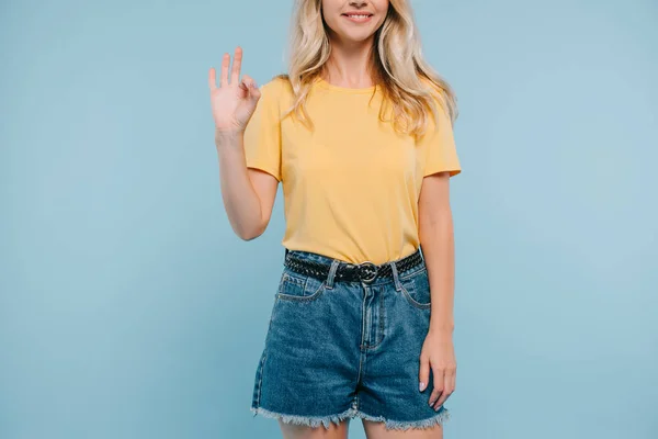 Cropped image of girl in shirt and shorts showing okay gesture isolated on blue — Stock Photo