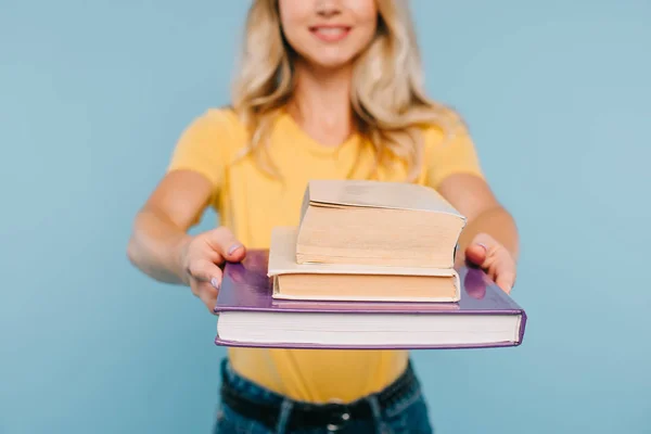 Imagen recortada de niña mostrando libros aislados en azul - foto de stock