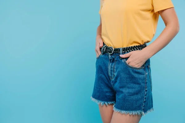 Abgeschnittenes Bild eines Mädchens, das mit Händen in Taschen auf blauem Grund steht — Stockfoto