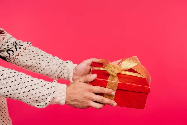 Imagen recortada del hombre en suéter dando regalo aislado en rosa — Stock Photo