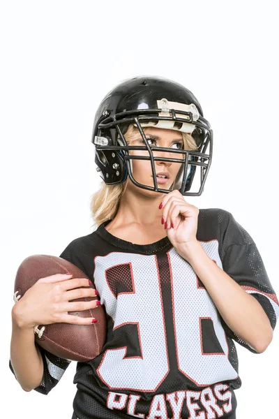 Mujer joven y deportiva en uniforme de fútbol americano con pelota aislada en blanco - foto de stock