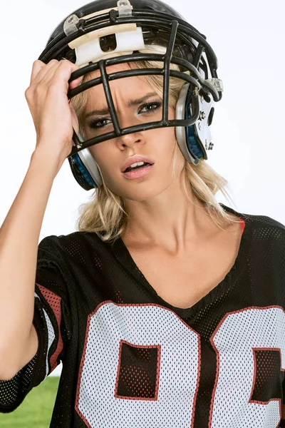 Nahaufnahme Porträt einer erschöpften jungen Frau in American-Football-Uniform, die ihren Helm isoliert auf Weiß auszieht — Stockfoto