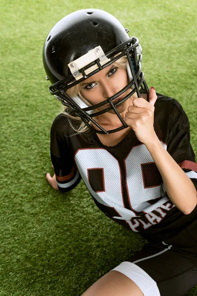 Raiva jovem mulher no americano futebol uniforme sentado na grama — Fotografia de Stock