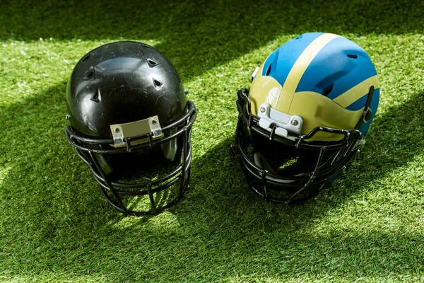Visão de alto ângulo de capacetes de segurança de futebol americano na grama verde — Fotografia de Stock