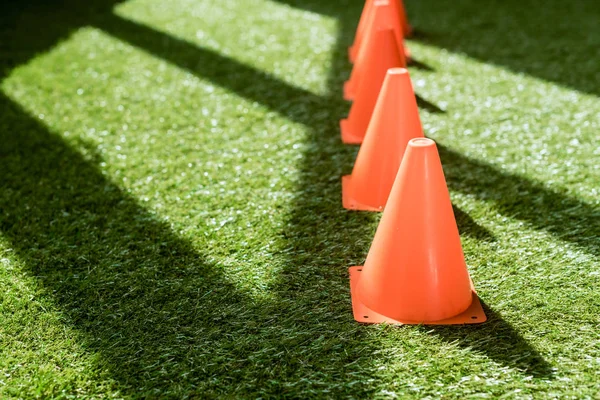 Tiro close-up de linha de cones de segurança em pé na grama verde — Fotografia de Stock