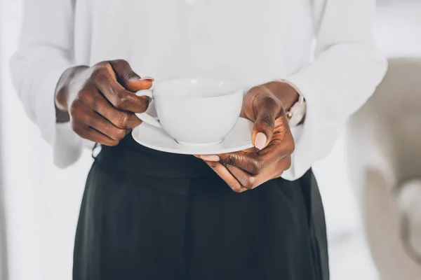 Immagine ritagliata di elegante donna d'affari africana americana in possesso di una tazza di caffè in ufficio — Foto stock