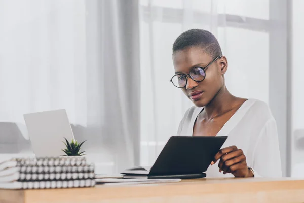 Élégant attrayant afro-américain femme d'affaires à la recherche dans carnet ouvert dans le bureau — Photo de stock