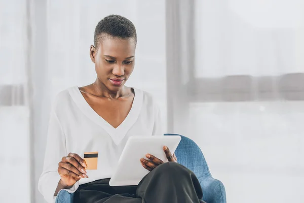 Bela mulher de negócios afro-americana compras on-line com tablet e cartão de crédito no escritório — Fotografia de Stock