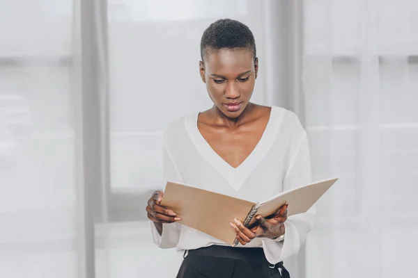Élégant attrayant afro-américain femme d'affaires lecture de documents dans le bureau — Photo de stock