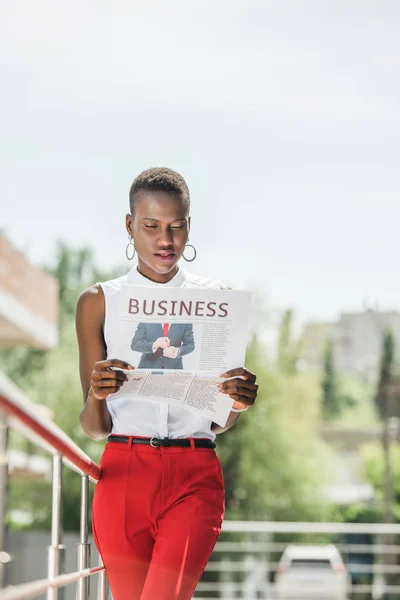 Модная привлекательная американская бизнесвумен читает деловую газету на улице — стоковое фото