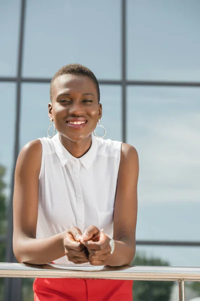 Portrait de heureuse femme d'affaires afro-américaine élégant appuyé sur la rampe près du centre d'affaires — Photo de stock