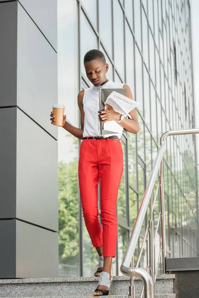 Vista a basso angolo di elegante attraente donna d'affari africana americana che calpesta le scale vicino al centro business — Foto stock