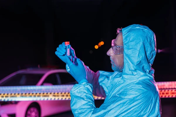 Visão lateral do criminologista de meia-idade em traje protetor e luvas de látex coletando evidências na cena do crime com cadáver — Fotografia de Stock