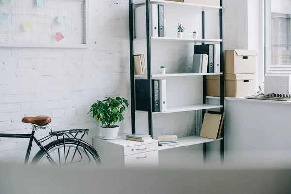 Bicycle and shelves with folders in light modern office — Stock Photo