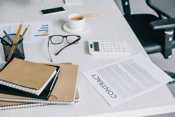 Notizbücher, Vertrag und Taschenrechner auf dem Tisch im hellen modernen Büro — Stockfoto